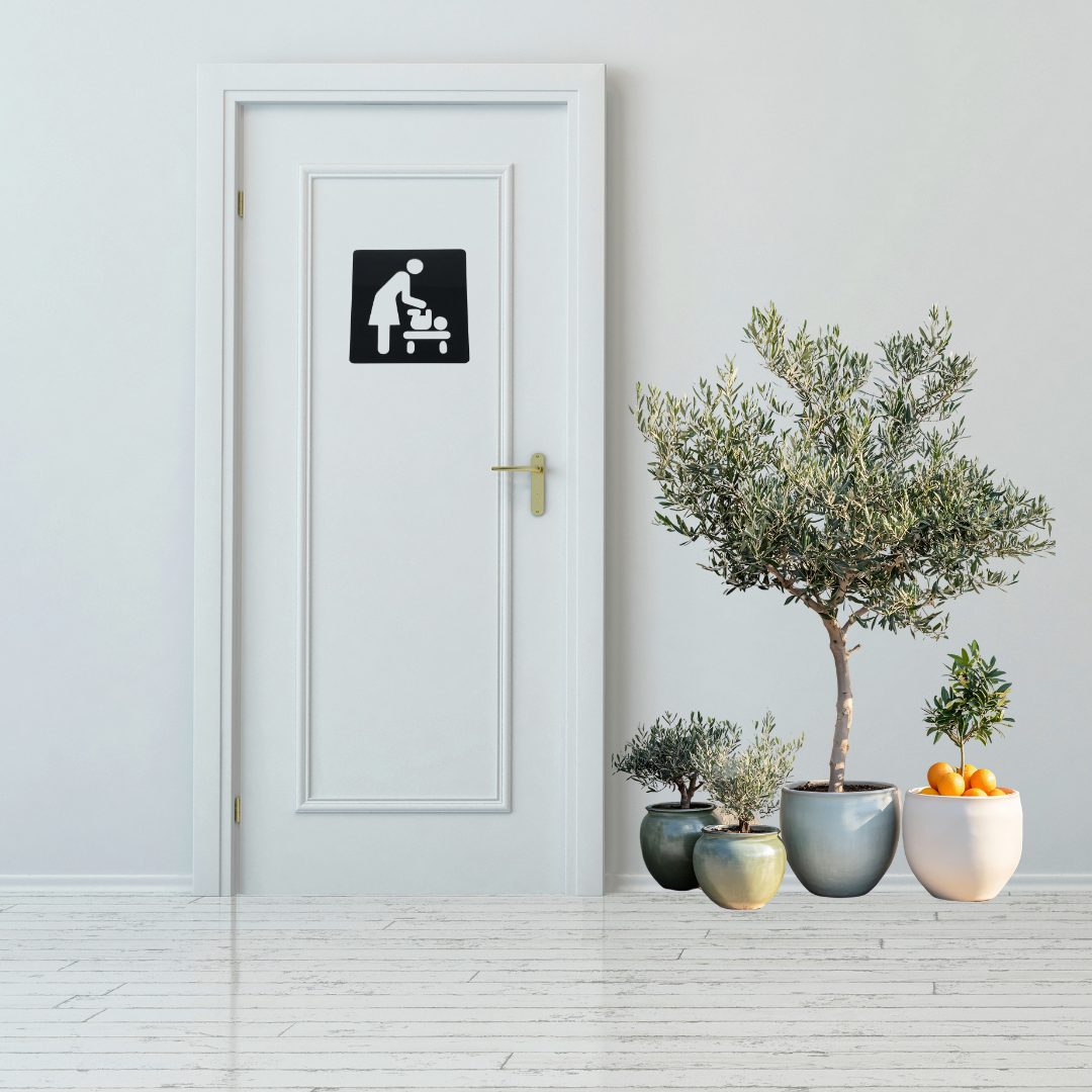 Baby Changing Station Metal Sign mounted on a modern restroom door.
