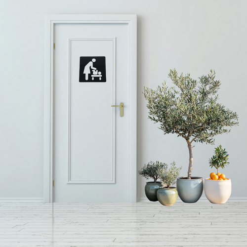 Baby Changing Station Metal Sign mounted on a modern restroom door.