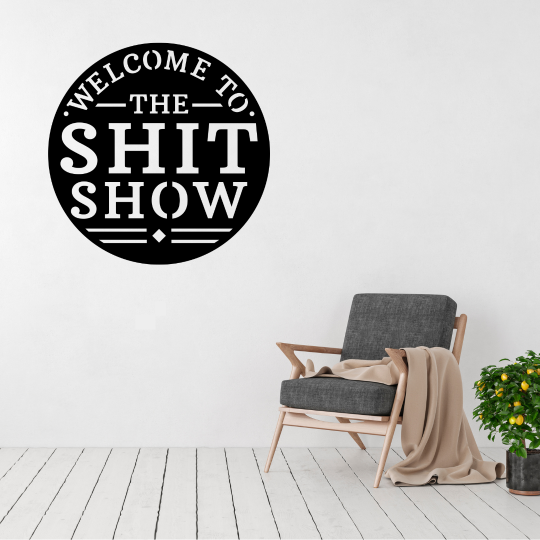 Chaos Welcome Welcome to the Shit Show metal wall art displayed above a contemporary chair in a modern interior