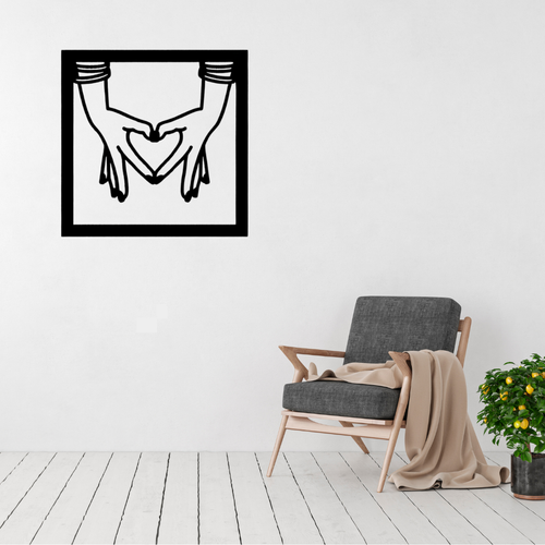 Connected Hearts | Holding Hands Metal Wall Art displayed on a modern living room wall above a grey accent chair, featuring two hands forming a heart within a contemporary square black metal frame.