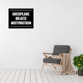 Discipline Beats Motivation motivational metal wall art displayed above a modern accent chair in a bright contemporary living room.