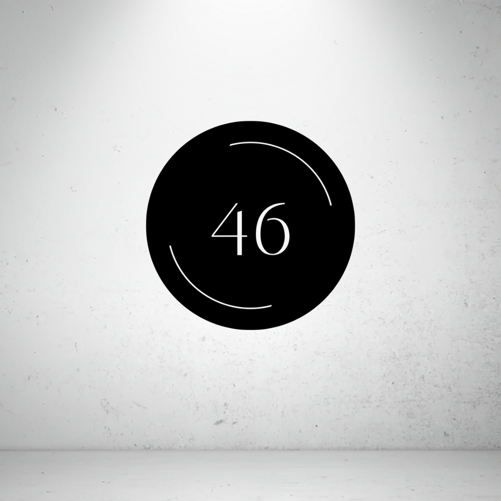 Modern circular metal house number sign with minimalist arc detailing and a custom house number.