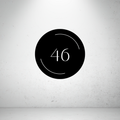 Modern circular metal house number sign with minimalist arc detailing and a custom house number.