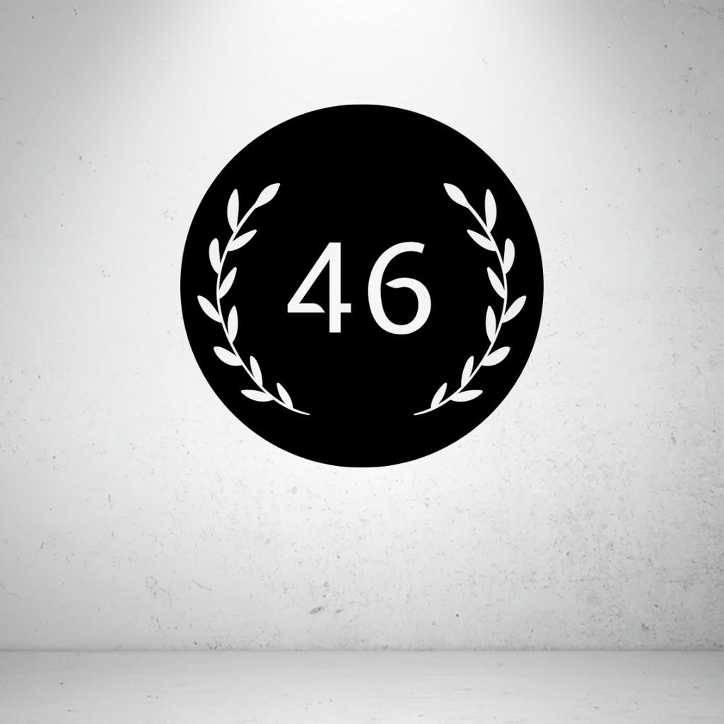 Circular metal house number sign with decorative botanical leaf detailing and a custom house number.