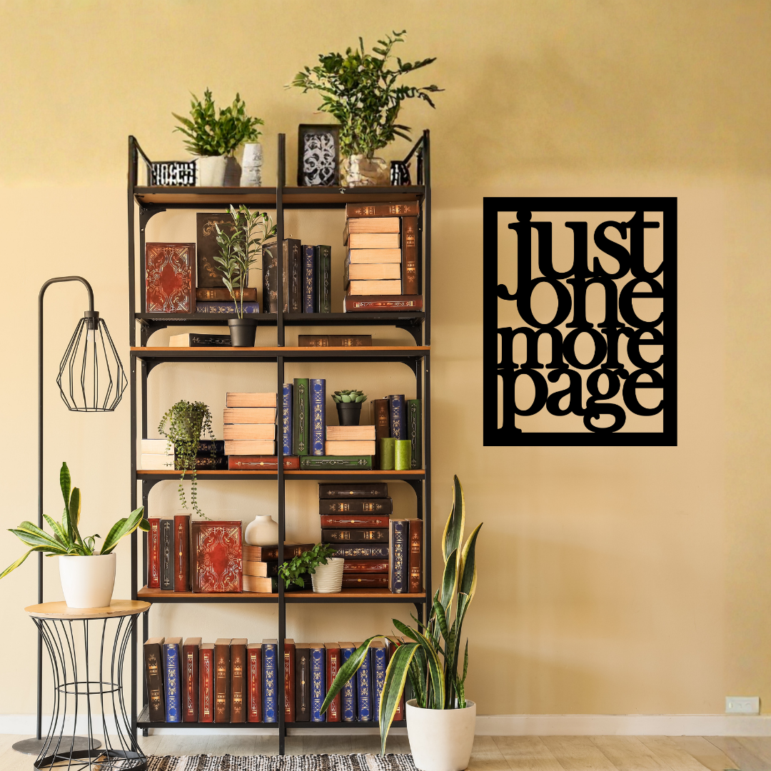 Just One More Page | Book Lover Metal Wall Art showcased on a feature wall beside a bookshelf filled with books and plants.