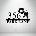 Metal house number sign with decorative key design on a grey background