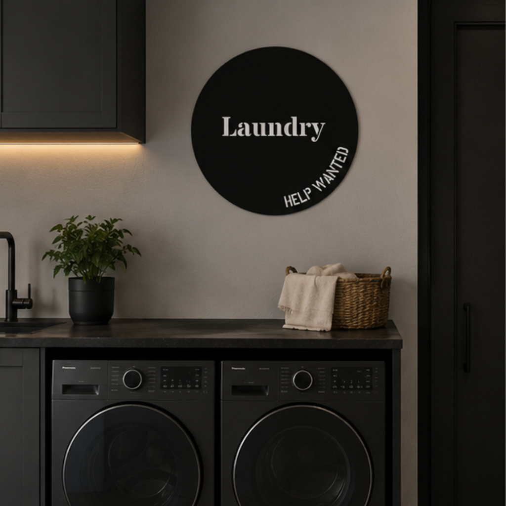 Black circular Laundry metal wall sign displayed above a contemporary laundry counter with modern appliances and minimalist décor.