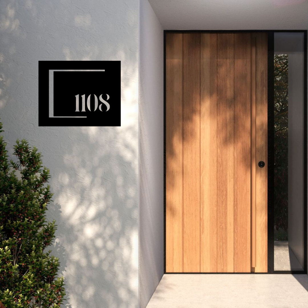 Modern framed house number sign installed on a rendered entrance wall beside a contemporary timber front door.