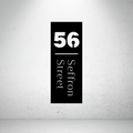 Modern vertical metal address sign featuring a custom house number and vertically displayed street name.