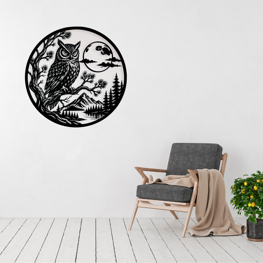 Moonlit Wisdom | Owl Circular Metal Wall Art displayed on a modern living room wall above a grey accent chair, featuring a detailed owl perched on a tree branch beneath a full moon with mountains and pine trees in black metal.