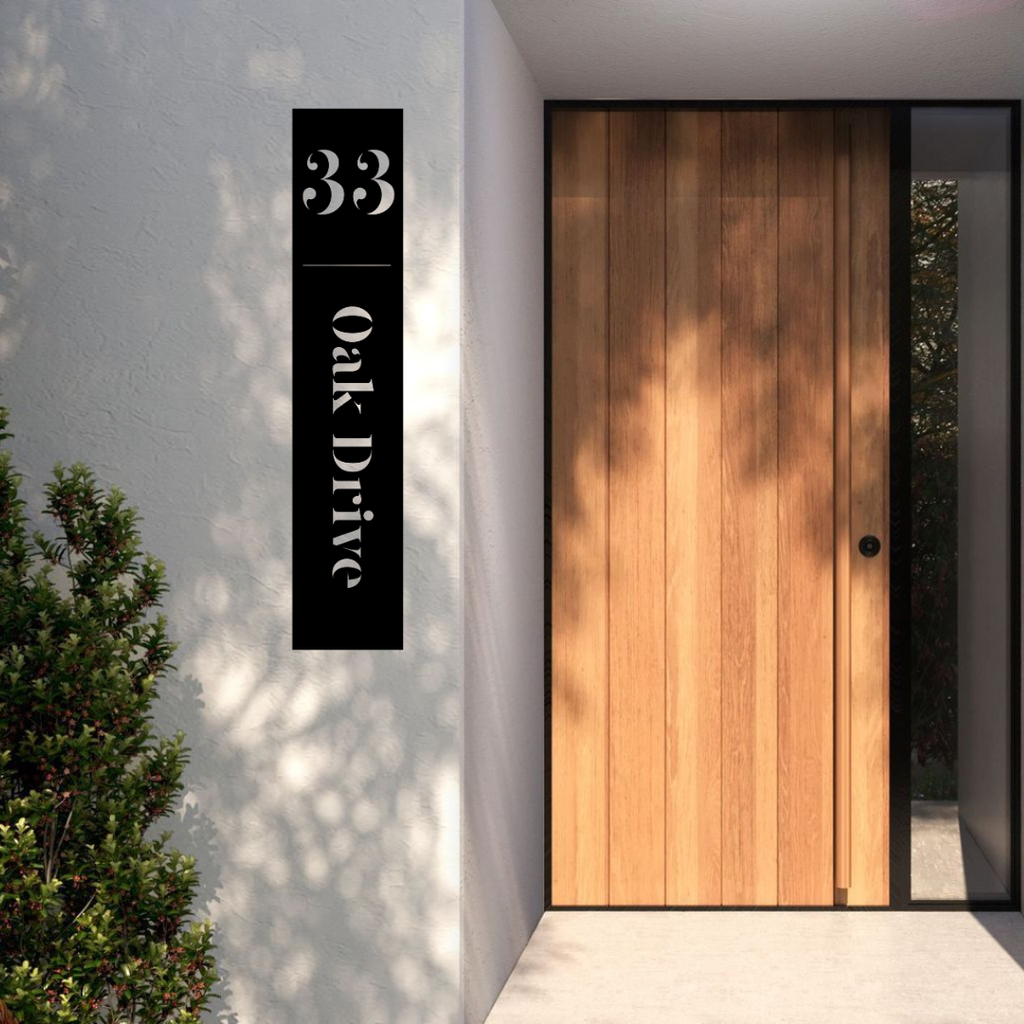 Oak Drive custom vertical metal address sign mounted on a modern rendered entrance wall beside a timber front door.