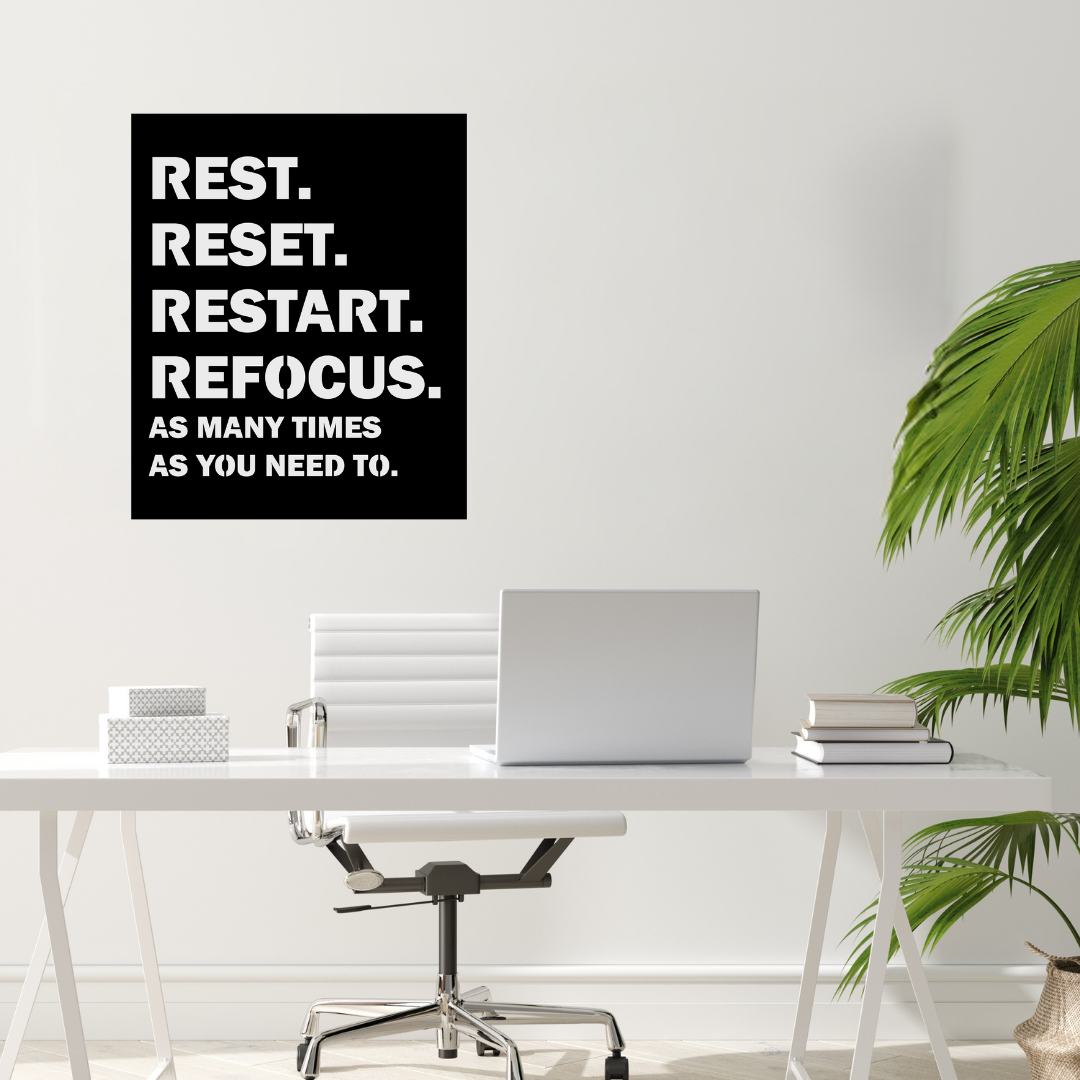 Reset & Refocus motivational metal wall art displayed above a modern office desk.