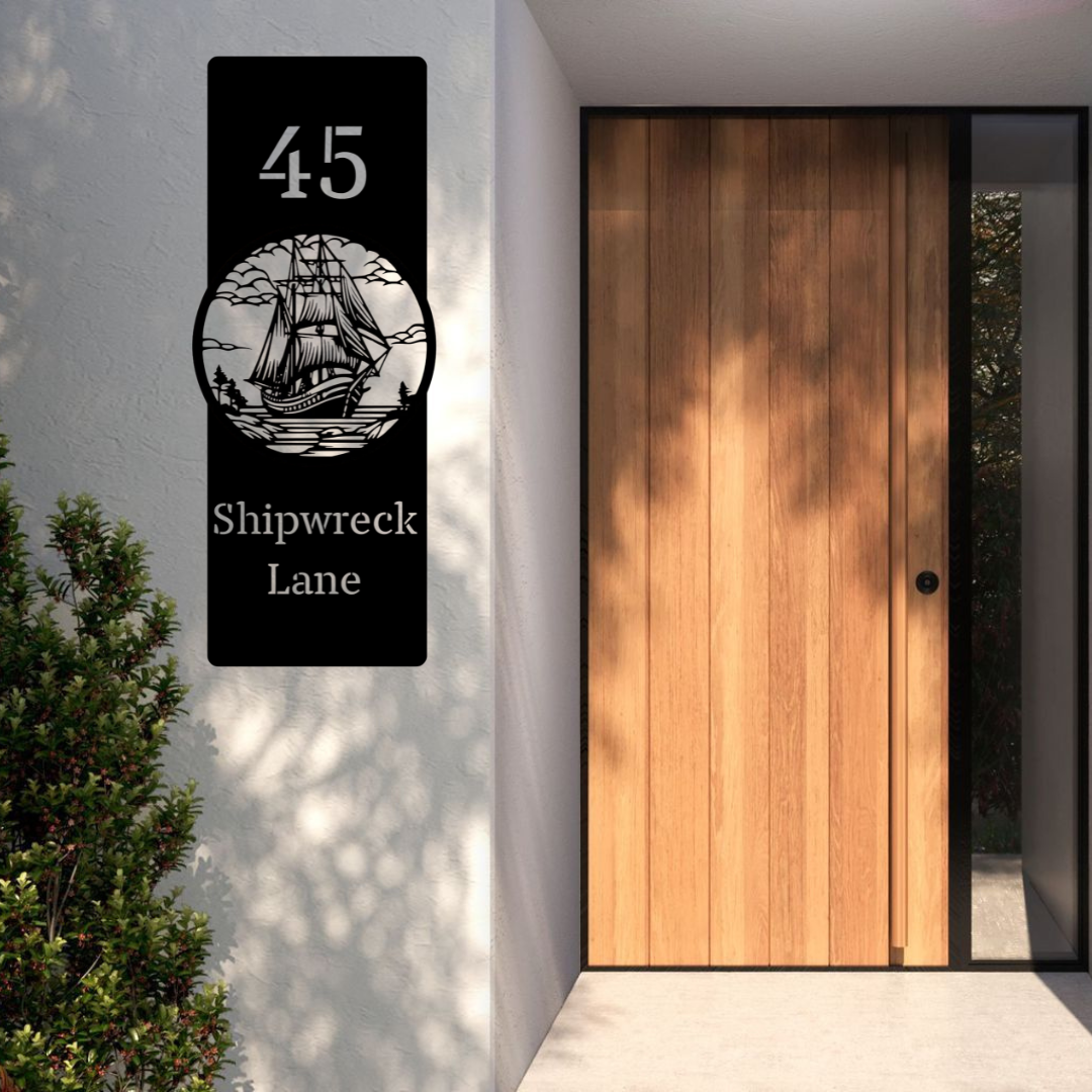 Shipwreck Lane vintage sailing ship custom vertical house number sign installed beside a modern timber front door on a rendered exterior wall.