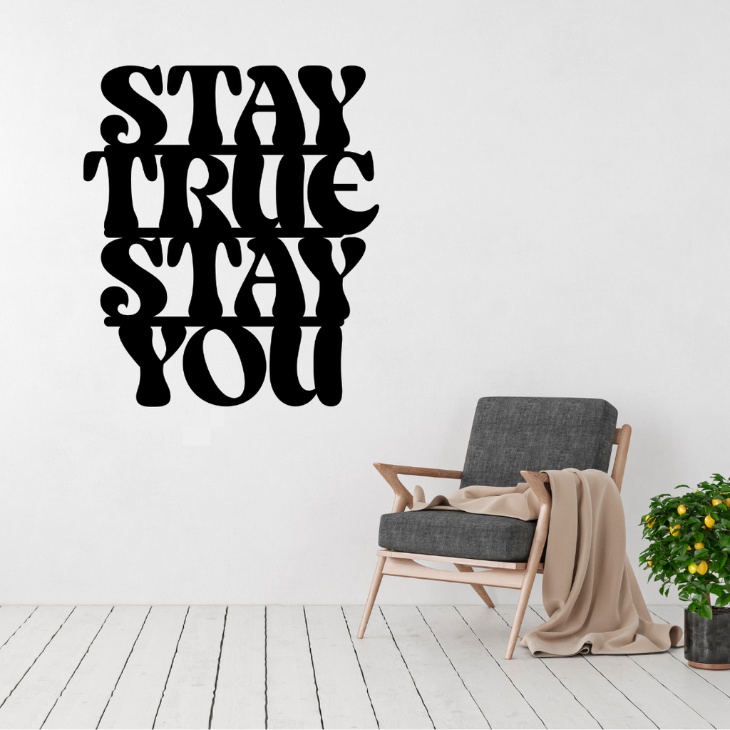 Stay True Stay You inspirational typography metal wall art displayed above a modern accent chair, featuring bold retro lettering laser-cut from premium steel.