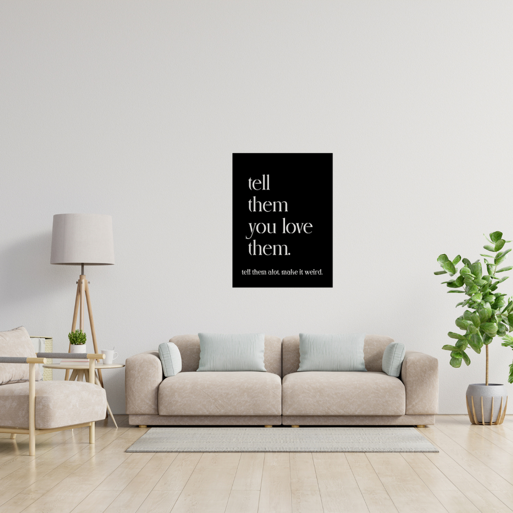 Tell Them You Love Them typography metal wall art displayed above a contemporary sofa in a bright modern living room.