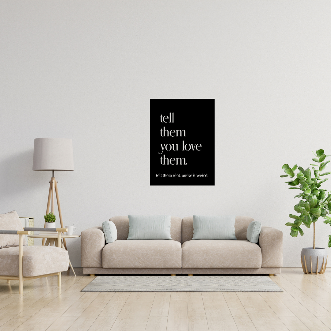 Tell Them You Love Them typography metal wall art displayed above a contemporary sofa in a bright modern living room.