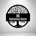 Metal house number sign with tree silhouette design on a grey background