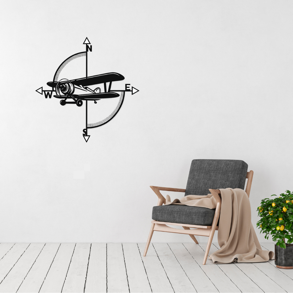Vintage airplane compass metal wall art displayed on a modern white wall above a lounge chair, creating a timeless aviation-inspired feature.