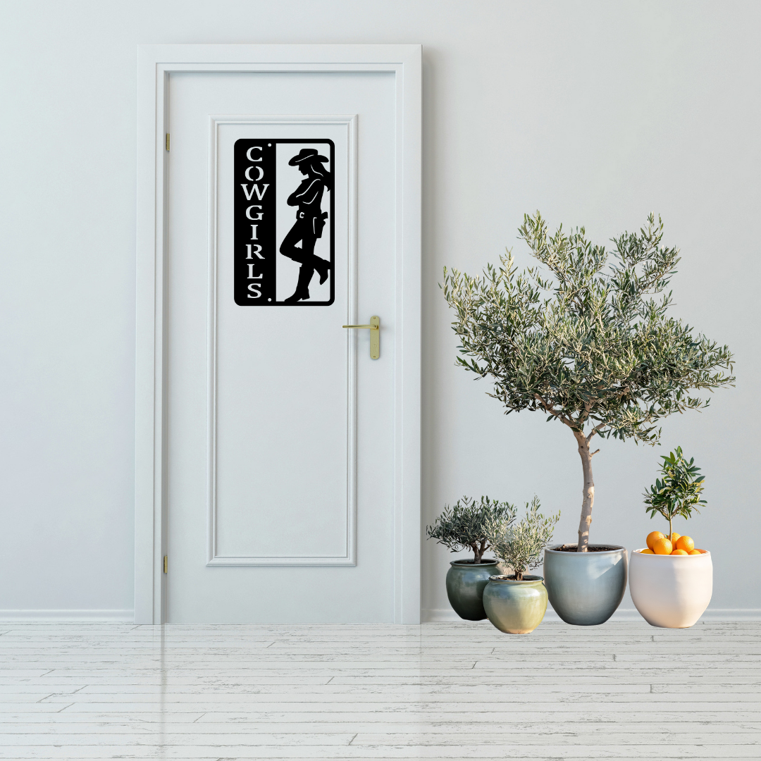 Western Charm | Cowgirls Bathroom Metal Wall Sign displayed on a modern white bathroom door.