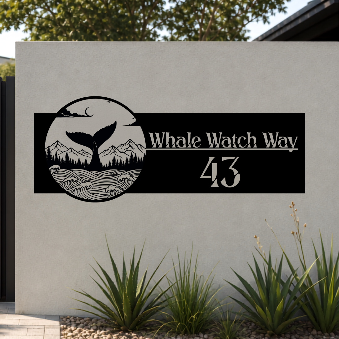 Whale Watch Way Whale Tail custom metal house number sign mounted on a modern rendered boundary wall beside a black aluminium sliding gate.
