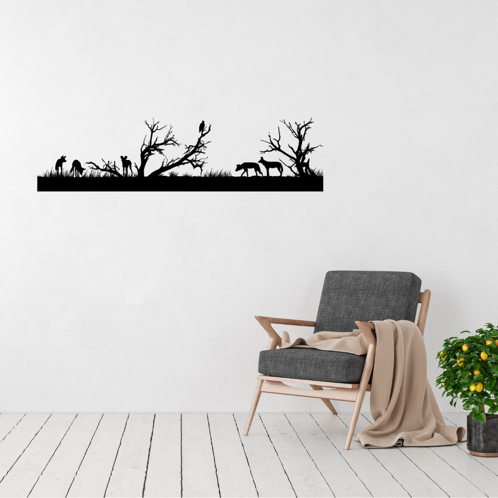 African savanna silhouette metal wall art featuring wild dogs, a vulture, trees and wildlife in a room with a contemporary chair.