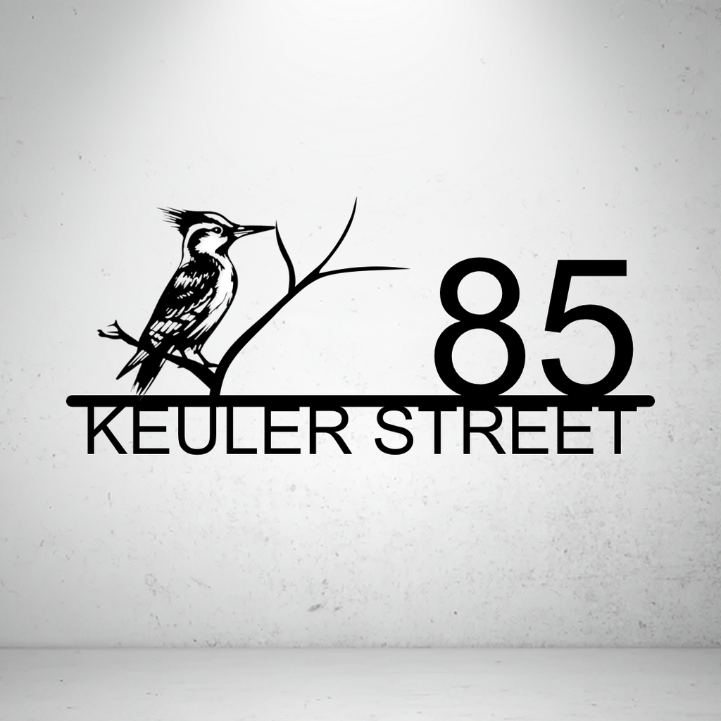 Metal house number sign with perched bird design on a grey background