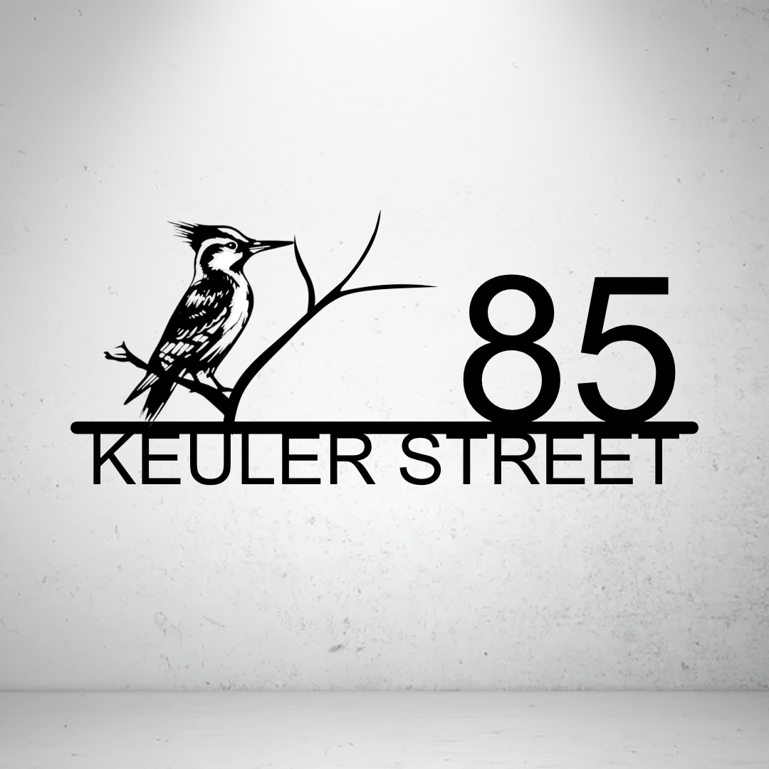 Metal house number sign with perched bird design on a grey background
