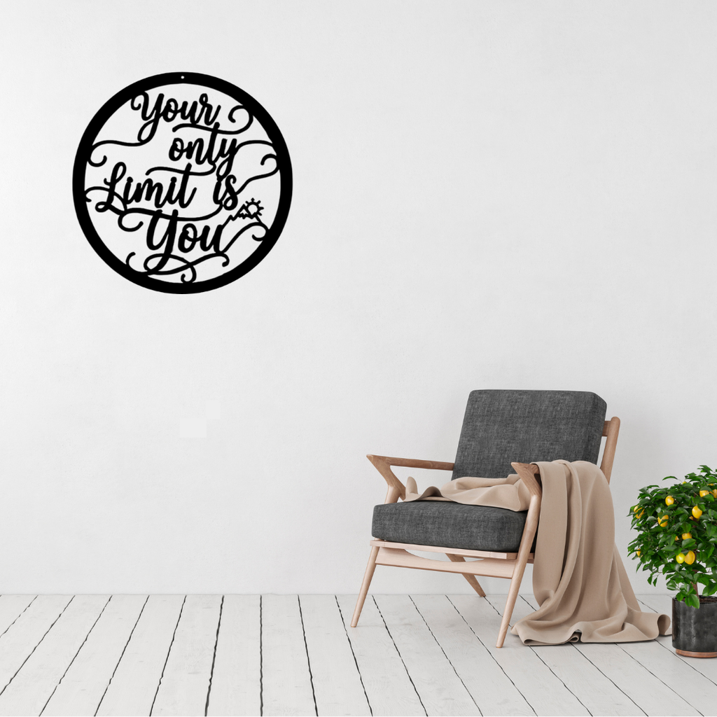 Your Only Limit Is You | Inspirational Metal Wall Art displayed on a modern living room wall above a grey accent chair, featuring motivational script typography inside a circular black metal frame.